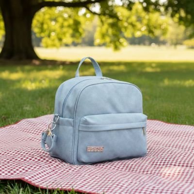 Sac a langer bleu ciel poser sur une nappe dans un parc vert 

